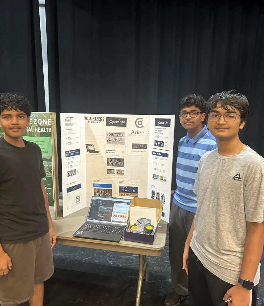 The three OpenByte co-founders standing by their technology education display with laptop and electronics kit